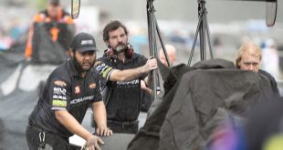 Race crews hurry to cover and move a dragster as the rain starts to fall Sunday during Gatornationals